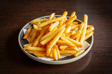 French fries in a plate on a dark wooden background