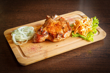 Grilled steak with onions and carrots on a wooden board.