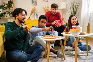Group of friends eating pizza and watching a movie in a shared student house.