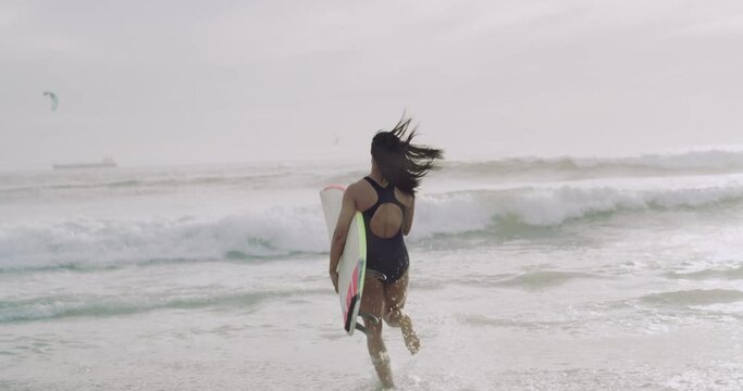 Back of surfer, running in ocean and surfboard at beach, extreme sports for fitness and adventure outdoor. Surfing, vacation and fun in swimsuit, hobby in nature and freedom with travel and tourism