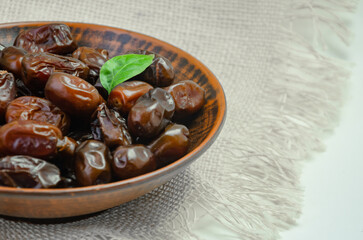 Dates in a brown plate on a textured light background, side view
