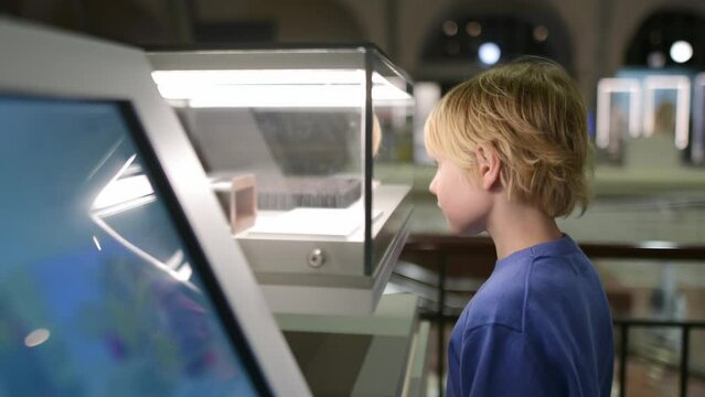 A child of primary school age visiting a science and tech museum. The boy is exploring a exhibit in a display case. Curious and smart child. Going to a museum as a family is quality time with kids.