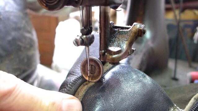 Repair of old shoes at a craftsman specialized in repairing all types of shoes. A very close-up of the needle on an old manual zipper quilting machine