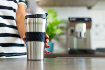 Hand Holding Stainless Steel Travel Mug in Kitchen