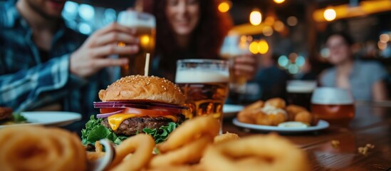 Friends enjoying a burger and onion rings while dining out. - obrazy, fototapety, plakaty