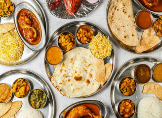 Assorted Indian thali chicken and mutton korma set with biryani, plain rice, pulao, chanay, tandoori chicken, palak, dal, mixed vegetable of aloo gobi matar, and chapati top view of indian spicy food