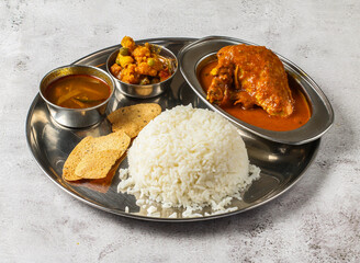 chicken thali set with chicken korma, boiled rice, mixed vegetable of aloo gobi matar and shorba served in dish isolated on background top view of indian spicy food