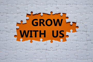 Grow with us symbol. Concept words Grow with us on white puzzle. Beautiful orange background. Business and Grow with us concept. Copy space.