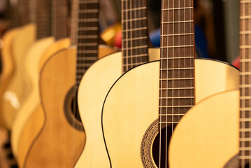 Closeup of row of different colorful guitars on the display for sale hanging in a music shop 