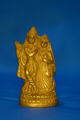 Miniature golden sculpture of hindu deities Radha Krishna isolated in blue background 
