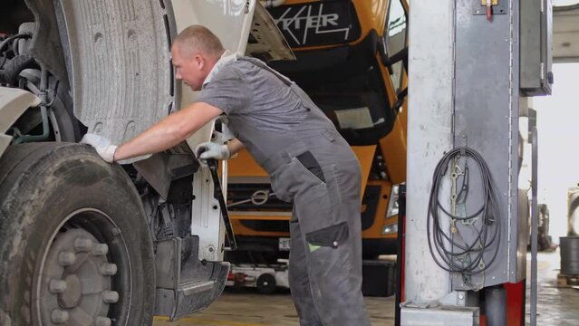 Auto mechanic lifts the cabin of a cargo truck