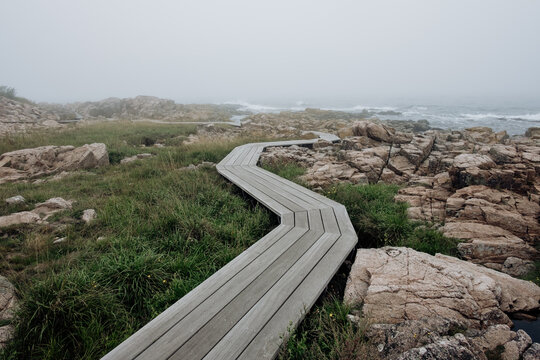 M&oslash;llen&aelig;sstien in Allinge, Bornholm. Walking on a wooden path through granite landscape near the sea on a misty day.