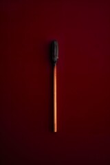 A practically extinguished match on a dark red background. Burning match in concept art representing lack of idea in empty red space.