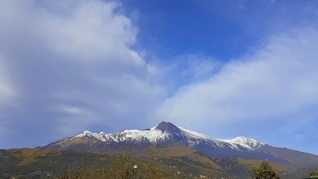 Panorama dell'Etna con un po di neve, cielo nuvoloso con uno spiraglio di azzurro.
