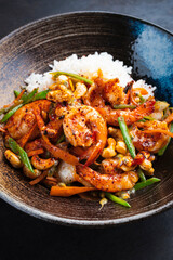 Traditional Thai fried king prawns with vegetable, cashew nuts and rice served as close-up in a design bowl