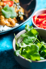 Close up of cilantro with chickpea curry and red peppers  in the background.