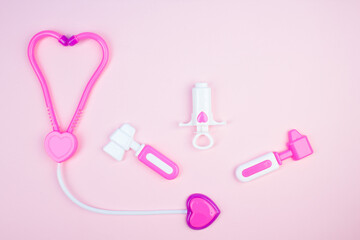 Obraz na płótnie Canvas The concept of a pediatrician. Pediatrics. Toy medical devices on a pink background. Children play professional doctor. Choice of profession. Get vaccinated.