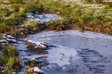 Obraz na płótnie Canvas Puddle with ice and crystals on a dirt road