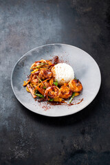 Traditional Thai fried king prawns with vegetable, cashew nuts and rice served as close-up on a design plate with text space