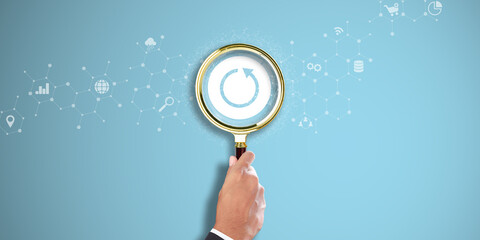 Backup. Businessman Hand Holding a Magnifying Glass with Backup Icon on Light Blue Background. Data...
