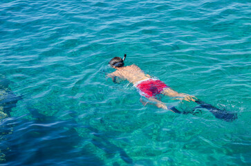 A boy dives in the sea with a mask and a snorkel. Summer holidays.