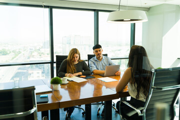 Two interviewers and a job candidate inside a meeting room conducting a job interview