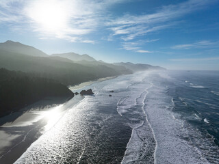 Sunlight shines down on the coast of Oregon near Cannon Beach. This scenic region, where forest meets the ocean, is known for its beautiful beaches, sea stacks, and tide pools.