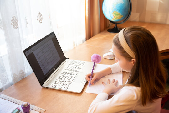 Online education of children. Girl schoolgirl teaches a lesson online using a laptop video chat call conference with a teacher at home.studying, participating in online conference, sitting at desk