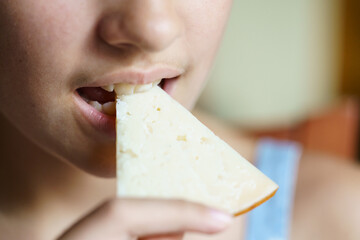 Crop young girl eating yummy cheese slice at home