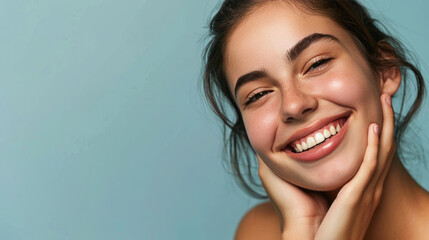 Smiling woman with a hand gently touching her face, displaying clear skin and a joyful expression.