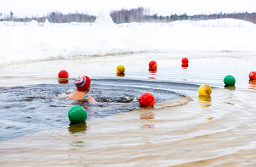Swimmer in icy waters at winter swimming competition marked by vibrant lane buoys
