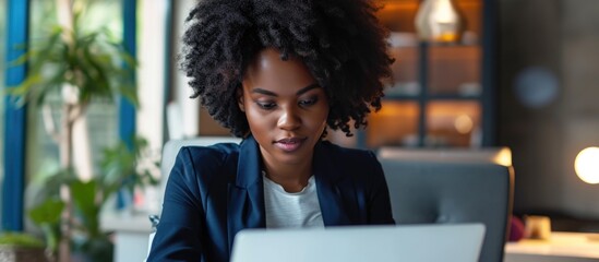 Black businesswoman working with laptop in office. African American female entrepreneur using computer, checking email, participating in online meeting.