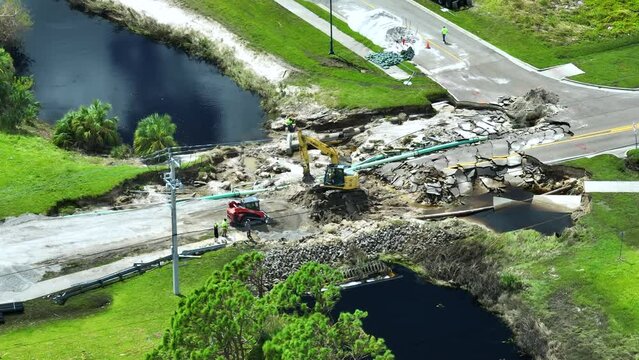 Aerial view of reconstruction of damaged road bridge destroyed by river after flood water washed away asphalt. Rebuilding of ruined transportation infrastructure.