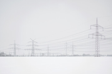 A lot of high-voltage power line in winter with lots of snow on the fields, electrical energy...
