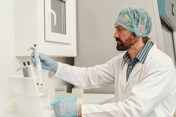 Focused scientist is using micropipette for biochemical test analysis in medical laboratory