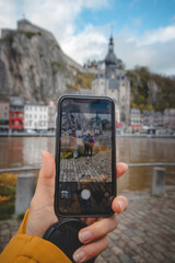 Couple in love standing on the banks of the river La Meuse in front of the landmark town of Dinant, photographed with a mobile phone. Daylight