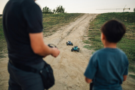 Focus on a toy race cars running to boy and father playing with them