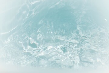 Bluewater waves on the surface ripples blurred. Defocus blurred transparent blue colored clear calm water surface texture with splash and bubbles. Water waves with shining pattern texture background.