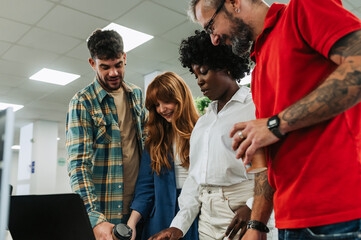 Obraz premium Portrait of diverse team looking at laptop at the office.