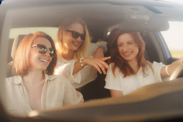 Three best friends share a laugh in a car on a sunny day, enjoying each other's company on a...