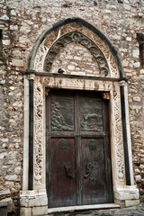Wooden, decorated door of a medieval stone church in Taormina on the island of Sicily