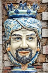 traditional porcelain decoration in the shape of a human head in the wall of a house on the island of Sicily