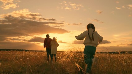 Children run together in park at sunset on grass. Happy family, teamwork. Running children, boy,...