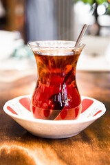 A glass of black Turkish tea on wooden table