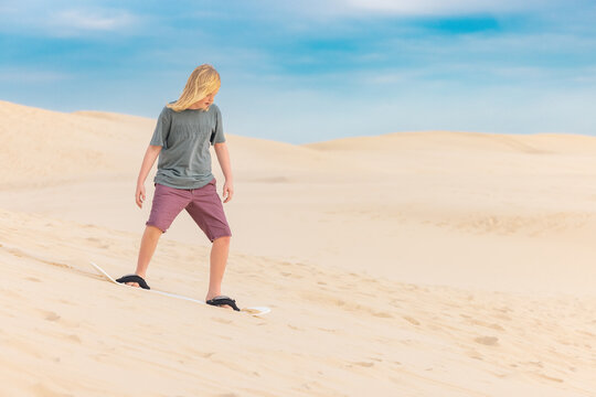 Boy sand boarding on the sand dunes at Birubi Beach in Port Stephens, NSW Australia