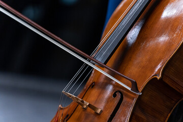 Close-up of strings and bow of a cello during a musical performance at an event