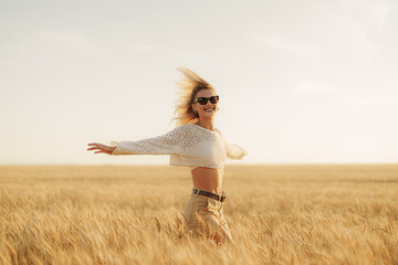 A woman exudes happiness as she spreads her arms wide, enjoying the freedom of the vast, golden...