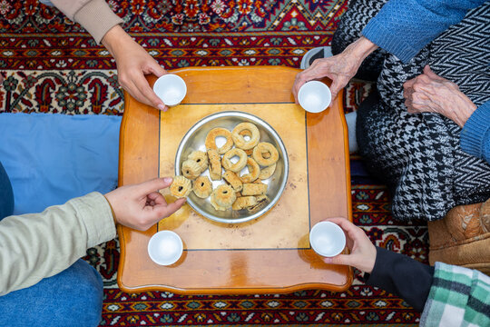 hands holding eid sweets and coffee cups, multigenerational family