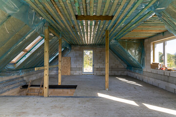 Fototapeta na wymiar Spacious attic under construction with thermal insulation and skylights in a new home