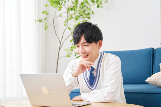 リビングでノートパソコンで動画を見る男子高校生